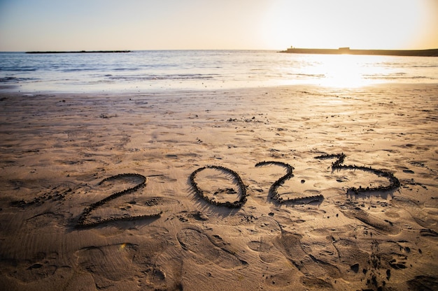 2023 napisany na plaży podczas zdjęcia zachodu słońca z miejsca na kopię