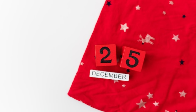 Zdjęcie 25 grudnia jest wyłożony czerwonymi kostkami wraz z grudniowym napisem na czerwonym bożonarodzeniowym tle wigilia