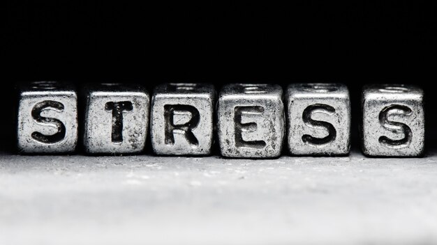 Zdjęcie 3d napis stres na metalowych kostkach na ścisłym czarnym szarym tle, koncepcja odporności na stres