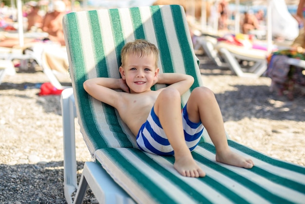 4-latek W Pasiastych Szortach Leży Na Leżaku Na Plaży Zadowolony I Szczęśliwy Lato