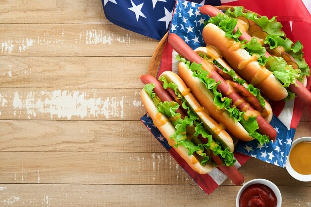 4 lipca Amerykański Dzień Niepodległości tradycyjne jedzenie piknikowe Hot dog z chipsami ziemniaczanymi i koktajlem Amerykańskie flagi i symbole USA Patriotyczne święto piknikowe na drewnianym tle Widok z góry