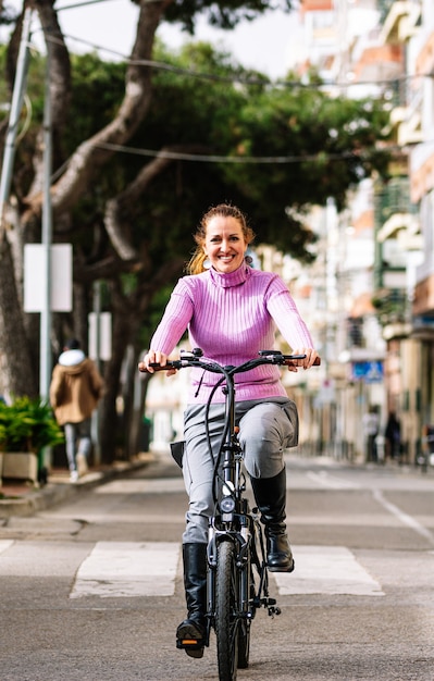 40-letnia kobieta jadąca na rowerze elektrycznym ulicami miasta (koncepcja mobilności elektrycznej)