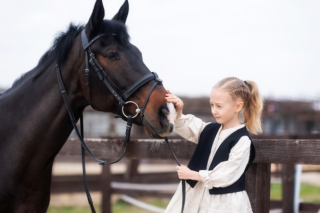 67-letnia dziewczynka głaszcze konia i chce go nakarmić trzymając konia za uzdę