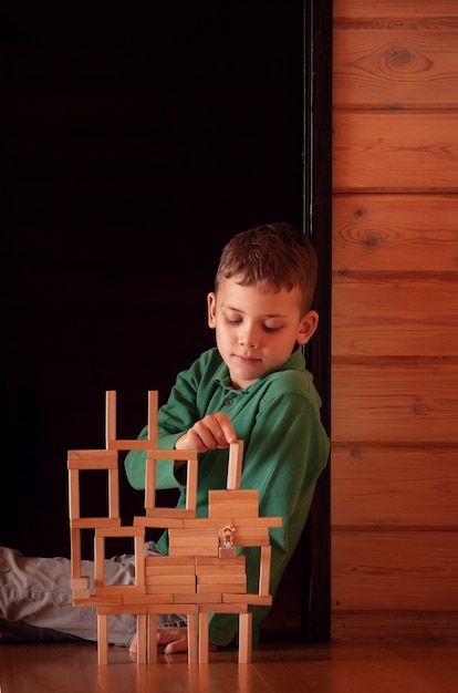 Zdjęcie 8-letni chłopiec bawi się drewnianymi elementami konstrukcyjnymi
