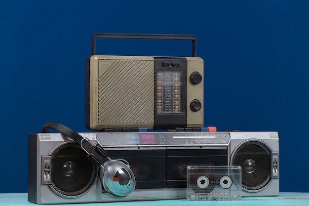 80s Retro przestarzały przenośny stereofoniczny magnetofon i odbiornik radiowy, słuchawki, kaseta audio na klasycznym niebieskim tle. Atrybuty lat 80., media retro, rozrywka