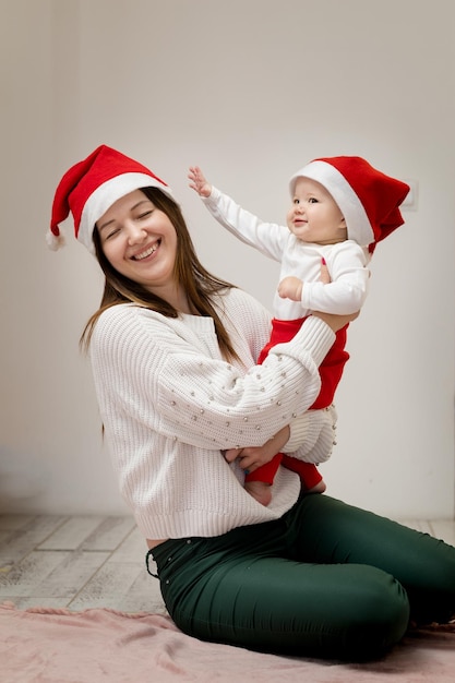 9-miesięczna dziewczynka próbuje zdjąć z głowy matki świąteczną czapkę, mama odwraca się i śmieje