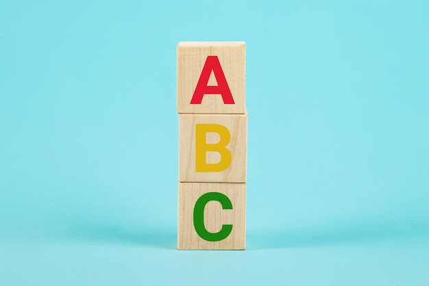ABC na drewnianych klockach ABC litery alfabetu na drewnianych kostkach w formie słupków na niebieskim tle