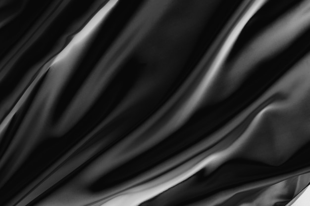 Abstrakcyjna czarna satynowa jedwabista tkanina na tło, tkanina tekstylna z zagnieceniami falistymi fałdami. Z miękkimi falami, falującymi na wietrze.