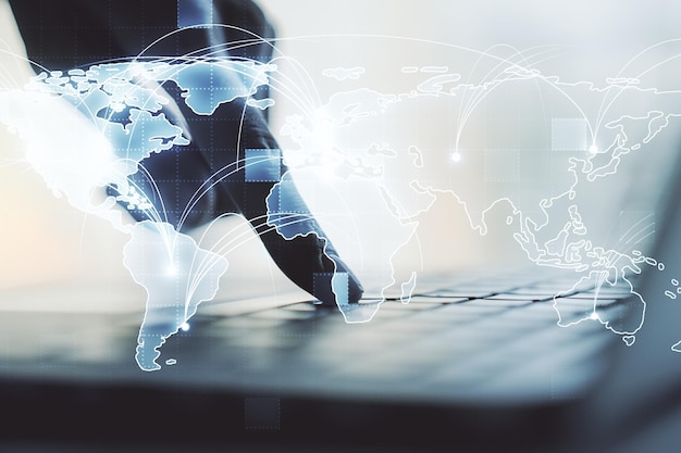Abstrakcyjna graficzna cyfrowa mapa świata z połączeniami i rękami piszącymi na klawiaturze komputera na tle koncepcji globalizacji
