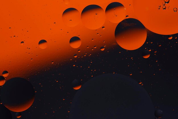 Abstrakcyjne pomarańczowe czarne tło z okręgami oleju na powierzchni wody