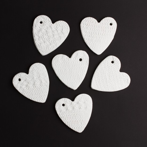 Abstrakcyjne serca wykonane z białej gliny porcelanowej na czarnym tle