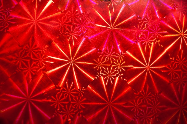 Zdjęcie abstrakcyjny wzór z promieniami na czerwonym papierze holograficznym.