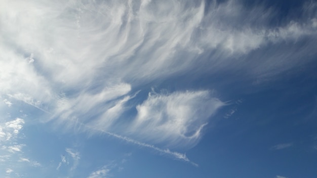 Abstrakt puszyste białe chmury z zmrokiem - niebieskie niebo na światło słoneczne dniu