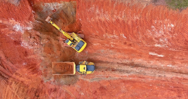 Aby przygotować grunt pod budowę, koparka ładuje wywrotki do ziemi i przenosi glebę, aby mogła być gotowa do budowy na placu budowy
