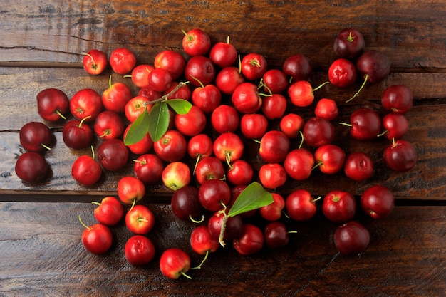 Acerola Cherry surowy, świeży, na rustykalnym drewnianym stole, wysoka witamina C i przeciwutleniacze