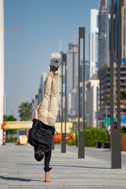 Acrobat utrzymuje równowagę jedną ręką z zamazanym pejzażem Dubaju