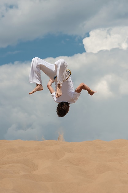 Acrobat wykonuje akrobatyczny trik, salto na plaży.