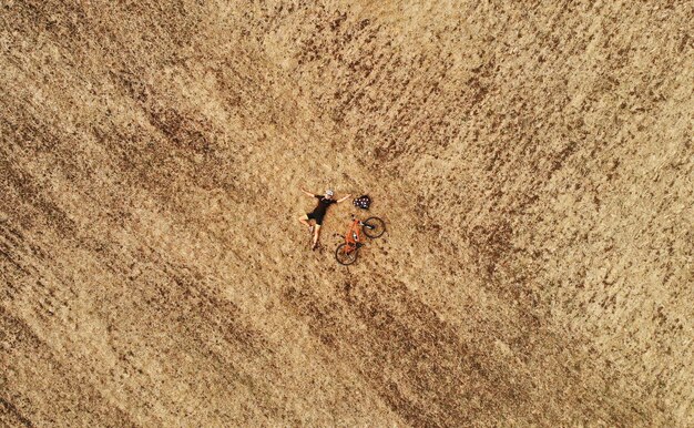 Aerial wakacje wycieczka zdjęcie dziewczyny rowerzysty leżącej na jesiennym polu z widokiem z góry pomarańczowy dron rowerowy