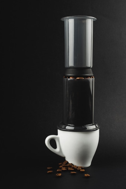 Aeropress z białymi ziarnami kawy filiżanka espresso na czarnym tle Aeropress do parzenia kawy