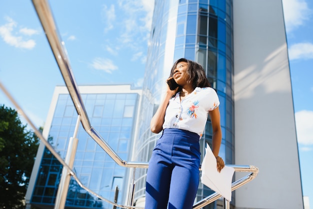 African American businesswoman przy użyciu telefonu komórkowego na ulicy przed budynkiem