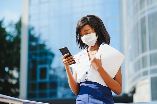 African American businesswoman przy użyciu telefonu komórkowego w masce