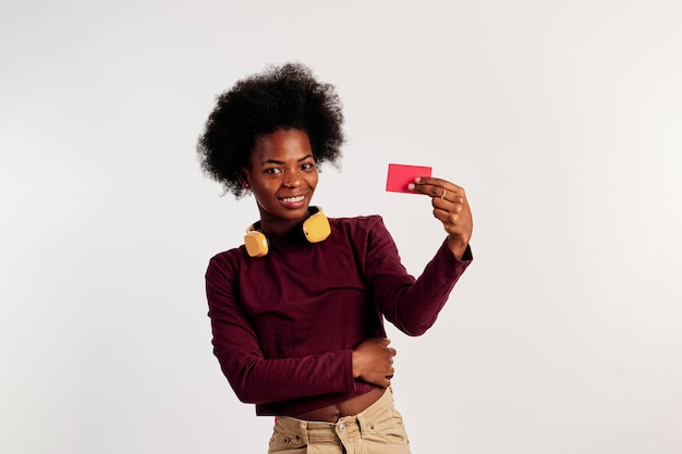 African American dziewczyna w brązowym swetrze pozuje pokazując jej kartę kredytową.