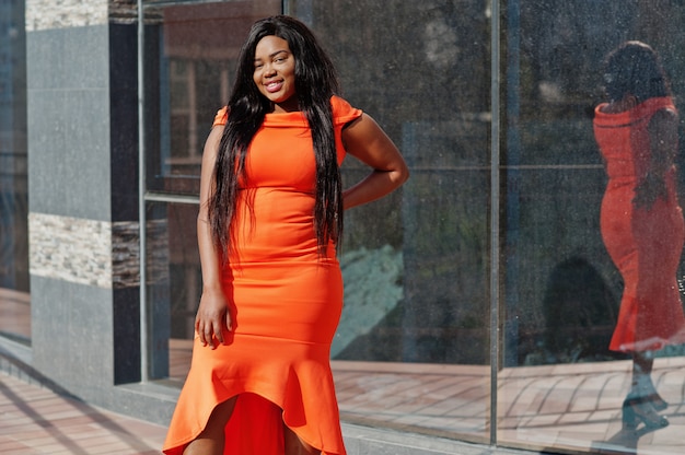 African American kobieta model XXL w pomarańczowej sukience.