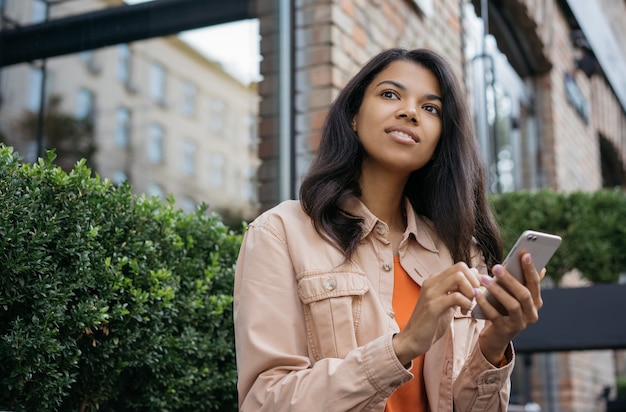 African American Kobieta Przy Użyciu Telefonu Komórkowego, Czekając Na Taksówkę Na Zewnątrz