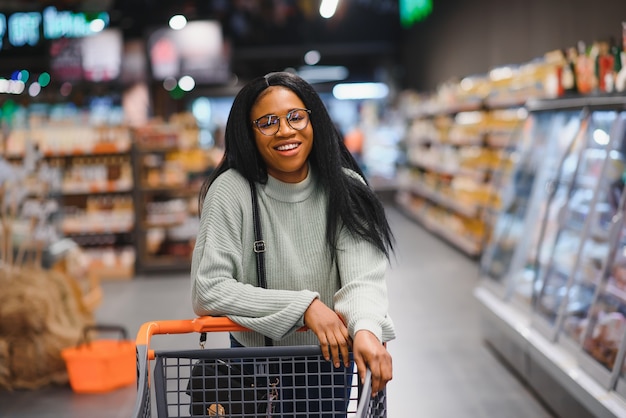 African american kobieta z wózkiem na zakupy w supermarkecie.