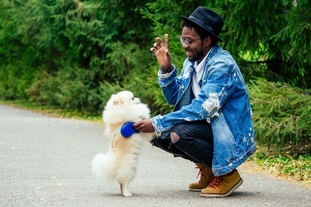 African american man chodzenia na ulicy ze swoim puszystym szpicem, nauczanie zespołów edukacyjnych psów.