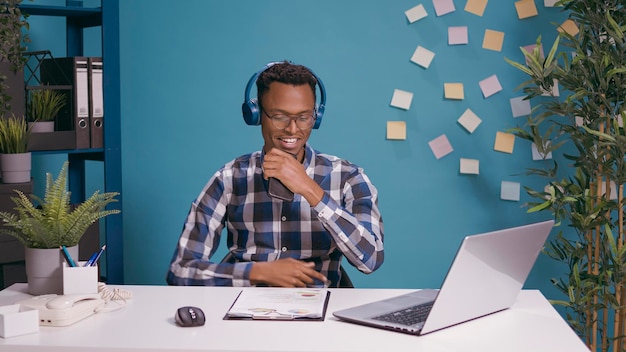 African american man nagrywania i śpiewania piosenki na smartfonie z zestawem słuchawkowym audio. Szczęśliwy dorosły słuchający muzyki mp3 i robiący sesję karaoke, używający telefonu komórkowego jako mikrofonu.