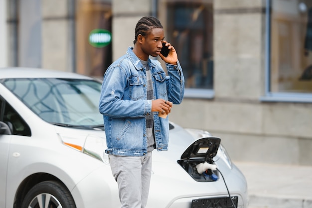 African American mężczyzna ładuje swój samochód elektryczny.