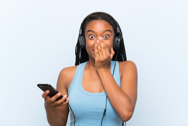 African American Nastolatka Dziewczyna Z Długimi Plecionymi Włosami Słuchania Muzyki Z Telefonu Komórkowego Z Niespodzianką Wyraz Twarzy