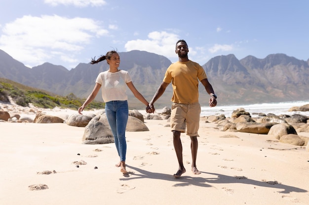 African american para spaceru trzymając się za ręce na plaży nad morzem. zdrowy styl życia, wypoczynek na łonie natury.