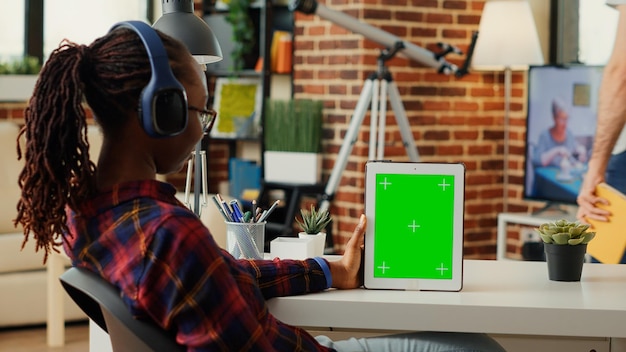 African american student patrząc na wyświetlacz greenscreen na cyfrowym tablecie, pracując z pustą makieta tła na urządzeniu. Używanie izolowanego klucza chrominancji w szablonie przestrzeni dcopy na przenośnym gadżecie.