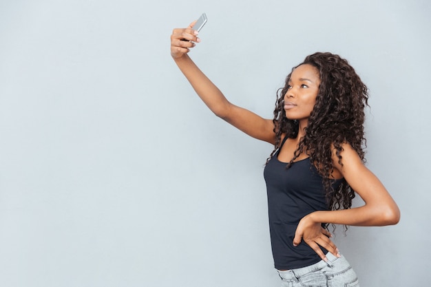 Afro American Kobieta Robi Selfie Zdjęcie Na Smartfonie Na Szarej ścianie