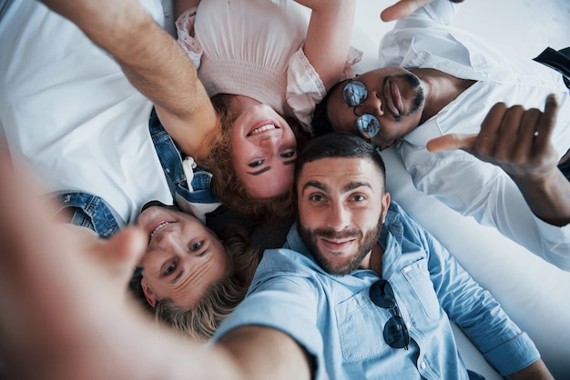 Afro amerykański facet pokazuje kciuk. Młodzi ludzie kładą się i robią selfie