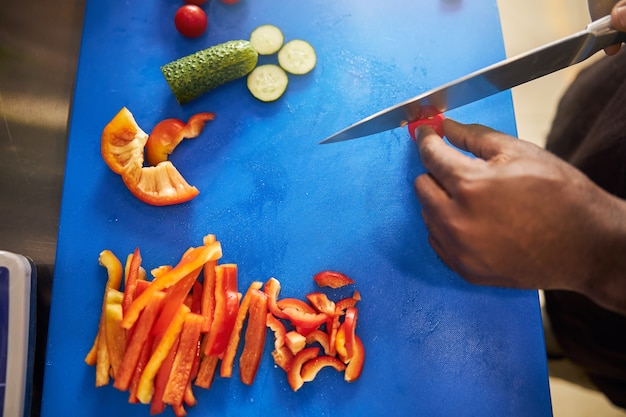Afro amerykański kucharz krojący pomidory na pokładzie nożem w profesjonalnej kuchni