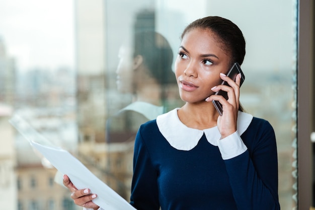 Afro Biznes Kobieta W Sukience Rozmawia Przez Telefon I Stoi Przy Oknie W Biurze