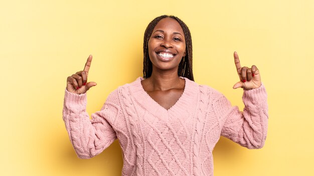 Afro czarna ładna kobieta oprawiająca lub zarysowująca własny uśmiech obiema rękami, wyglądająca pozytywnie i szczęśliwie, koncepcja wellness