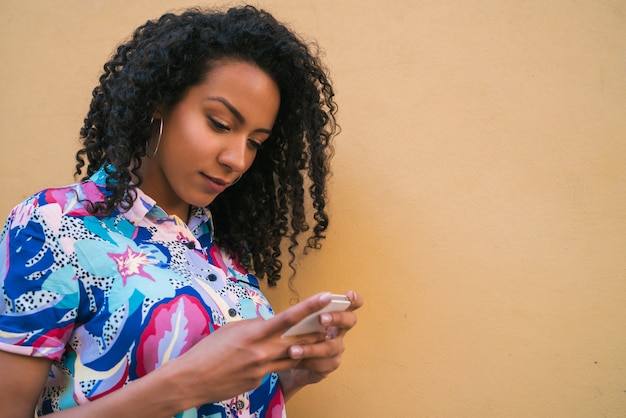 Afro kobieta używa jej telefon komórkowego.