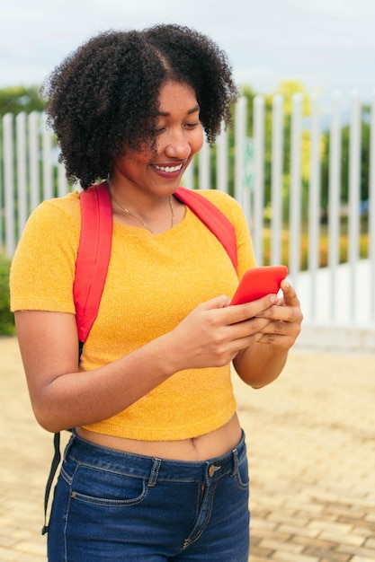 Afro kobieta używająca smartfona spacerująca po ulicy