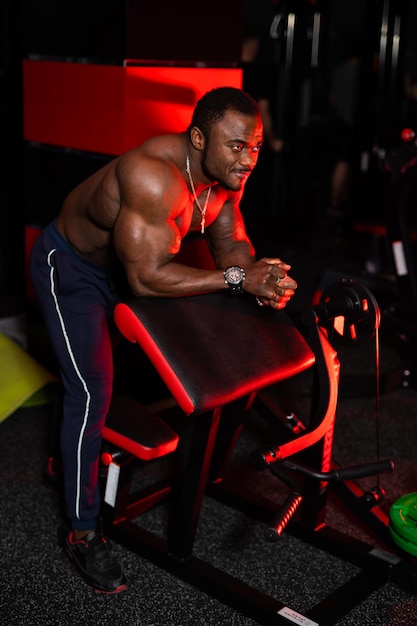 Afroamerykanin bez koszuli z silnym abs i idealnym ciałem Przystojny sportowiec na tle nowoczesnej siłowni