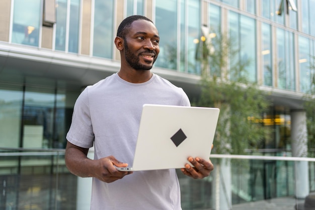 Afroamerykanin freelancer używający laptopa piszący czat na ulicy w mieście facet mający