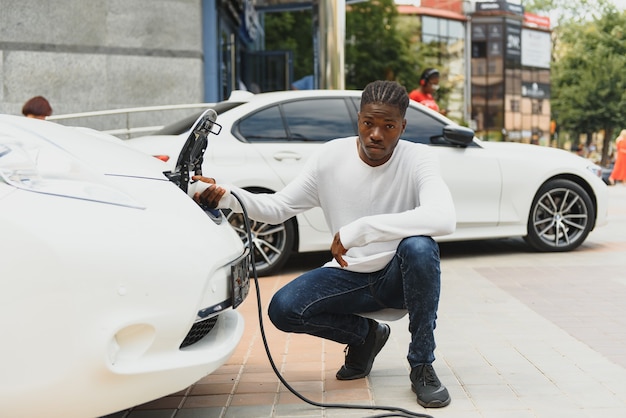 Afroamerykanin ładuje swój samochód elektryczny.