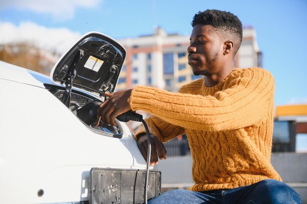 Afroamerykanin ładuje swój samochód elektryczny.