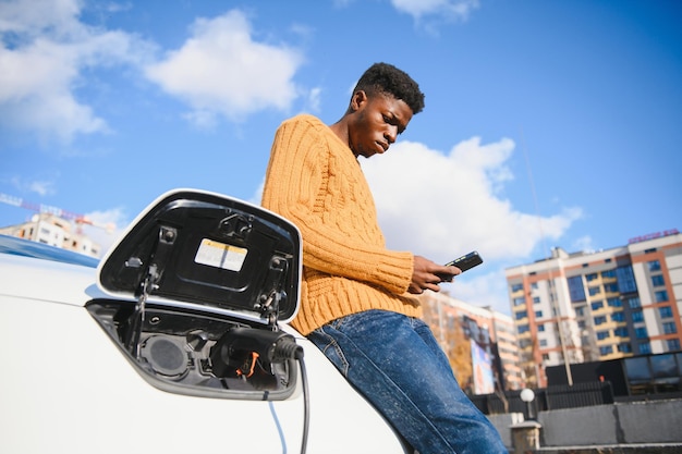 Afroamerykanin ładuje swój samochód elektryczny.