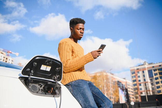Afroamerykanin ładuje swój samochód elektryczny.
