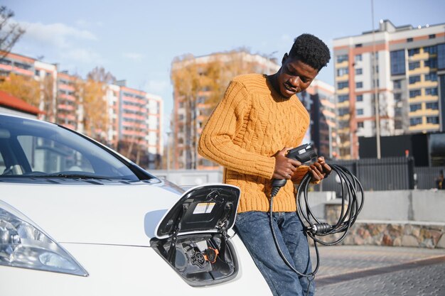 Afroamerykanin ładuje swój samochód elektryczny.