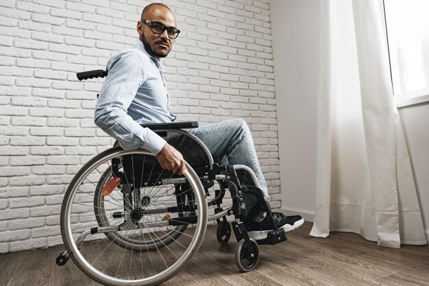 Afroamerykanin na wózku inwalidzkim siedzi samotnie przy oknie w domu